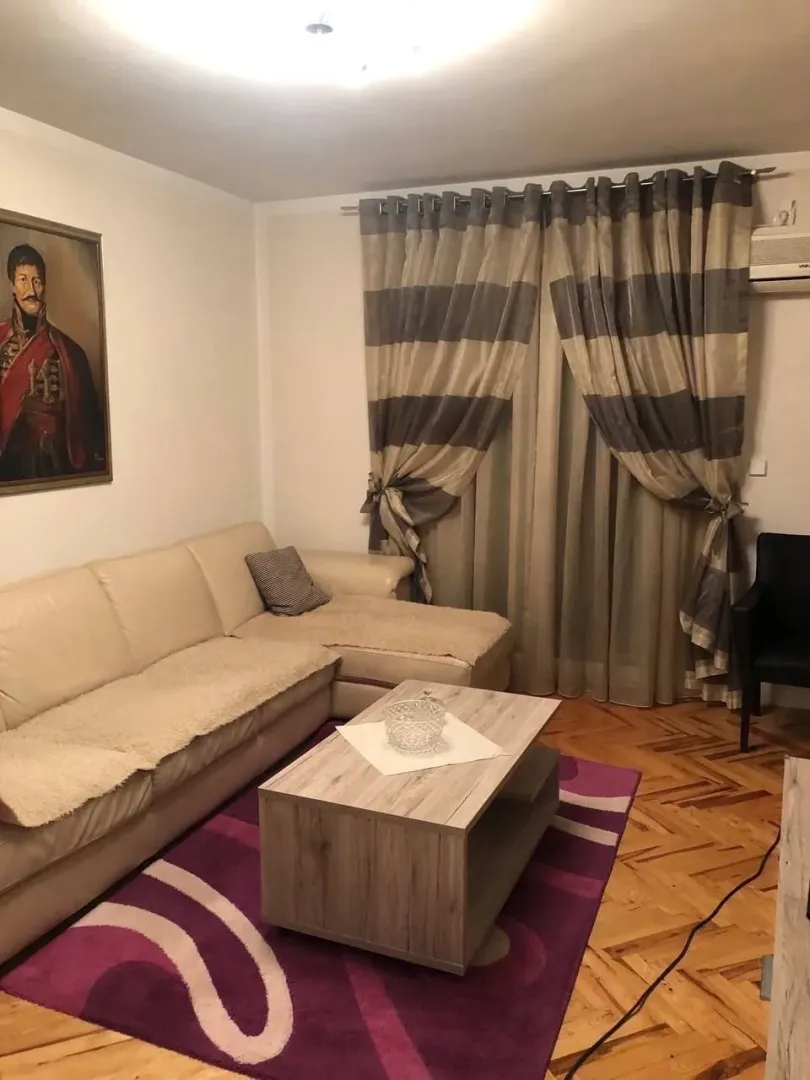 Living room with a sectional sofa, coffee table, and a window with curtains.