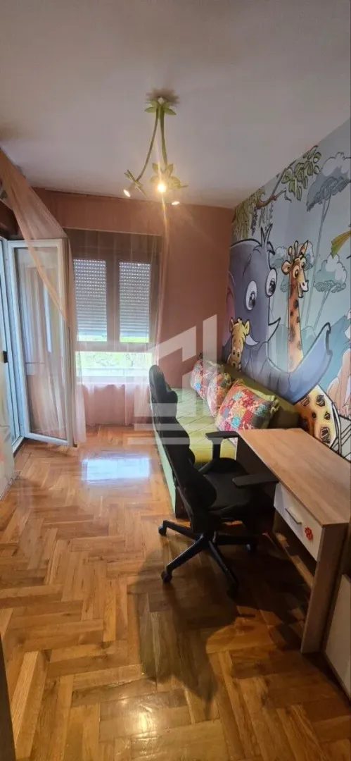 Children's bedroom with a bed, desk, and animal-themed wallpaper.
