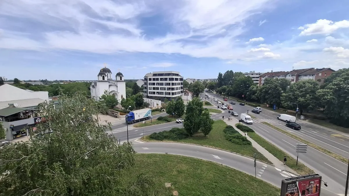Pogled sa prozora na okolne ulice, zgrade i crkvu.