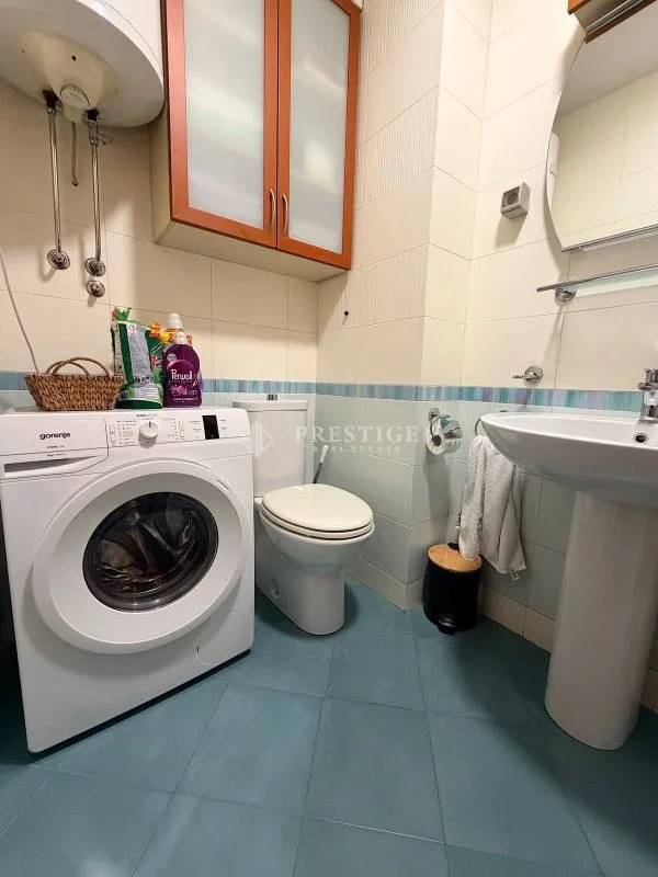 Small bathroom with a washing machine, sink, and toilet.