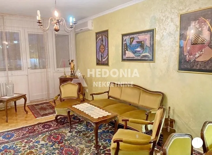Dnevna soba sa garniturom i umetničkim slikama na zidu.
