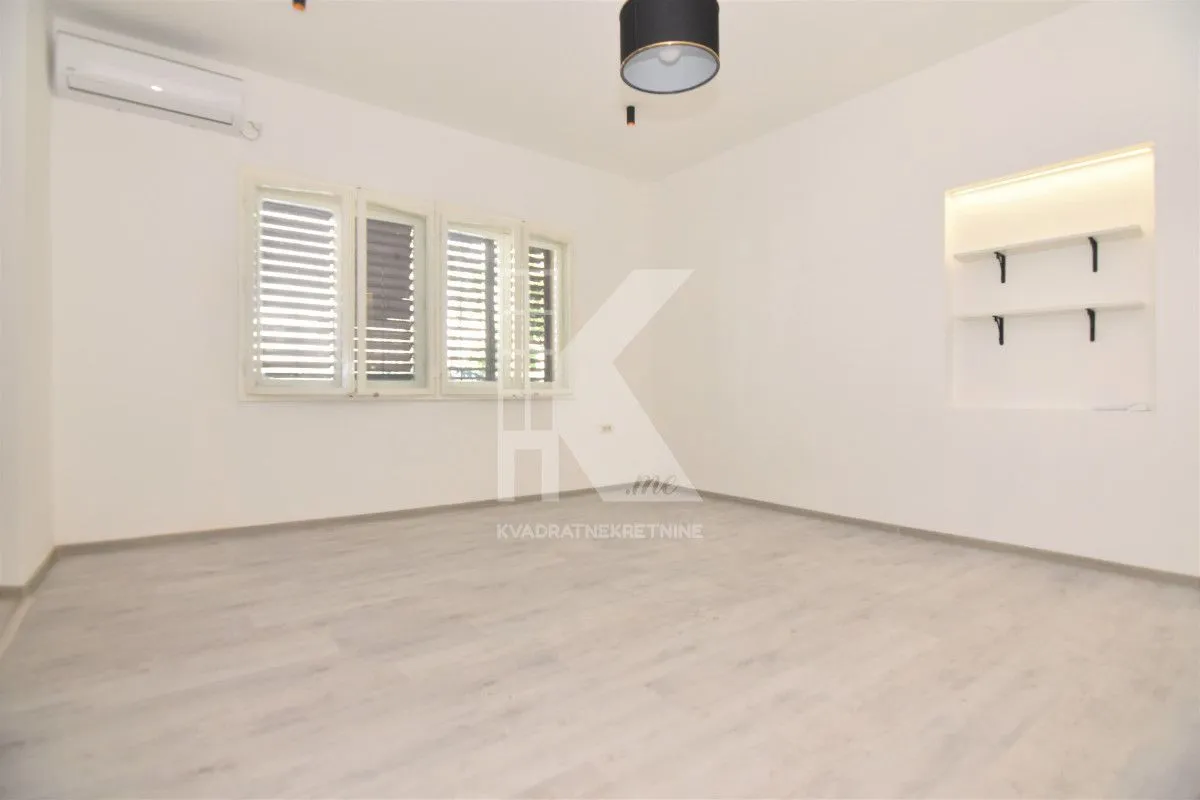 Empty bright room with windows, air conditioning unit, and built-in wall shelves.