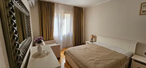 Namještena spavaća soba sa bračnim krevetom, foteljom i velikim ogledalom na zidu. - image 10