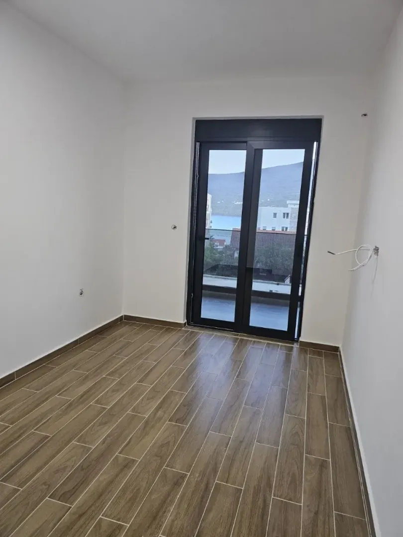 Prazna soba sa keramičkim podom i balkonskim vratima.