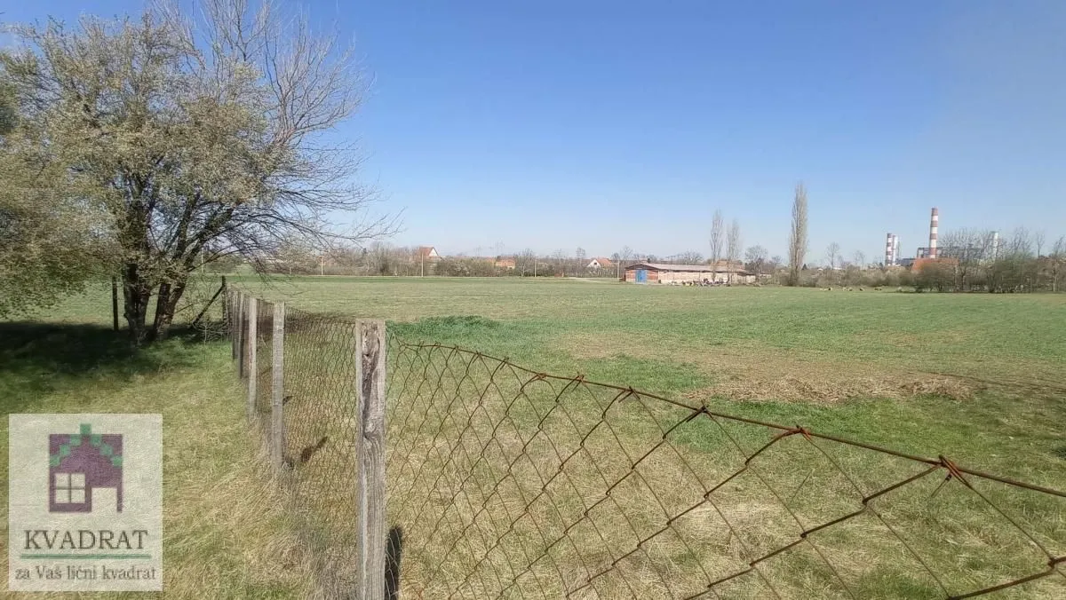 Pogled na ograđeno travnato dvorište i okolni pejzaž.