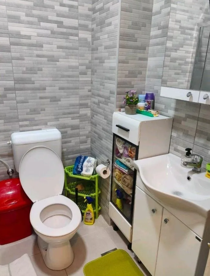 Small bathroom with toilet, washbasin, and grey tiles.