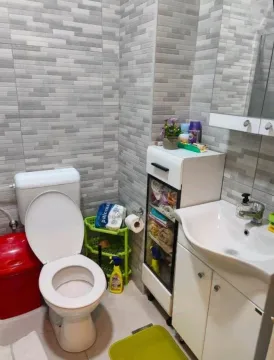 Small bathroom with toilet, washbasin, and grey tiles. - image 5