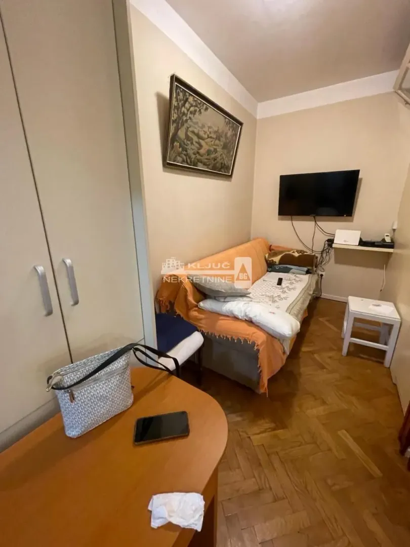 Manja dnevna soba sa kaučem, televizorom i plakarom.