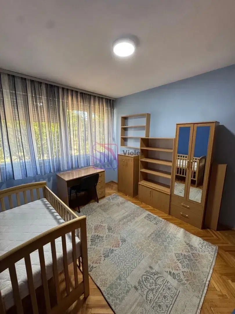 Children's bedroom with a crib, desk, wardrobe, and shelves.