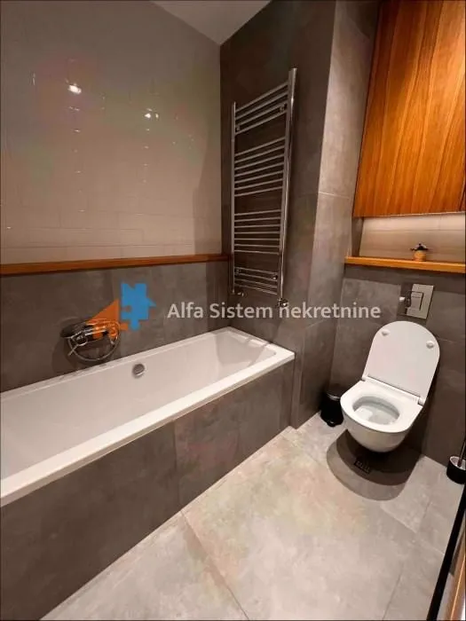 Moderno kupatilo sa kadom, wc šoljom i zidnim radijatorom.