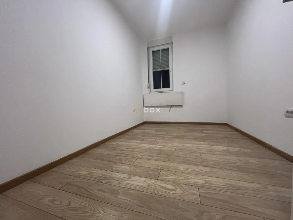 Empty room with white walls, wooden flooring and a window.