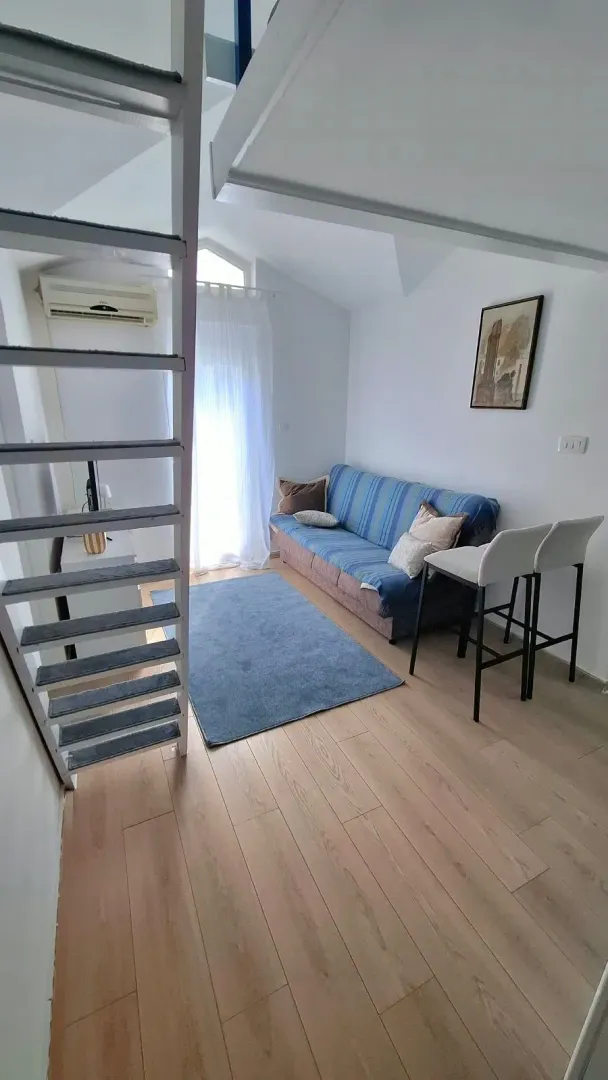 Living room with a sofa, rug, and stairs leading to the loft.