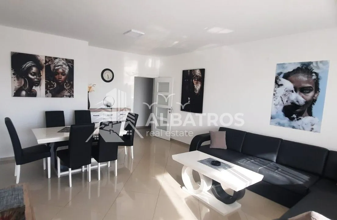 Living room with a dining area, a black sectional sofa, and a dining table with chairs.