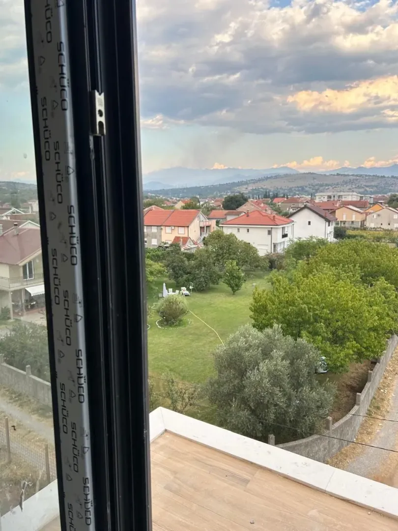 Pogled sa prozora na okolno naselje i prirodu.
