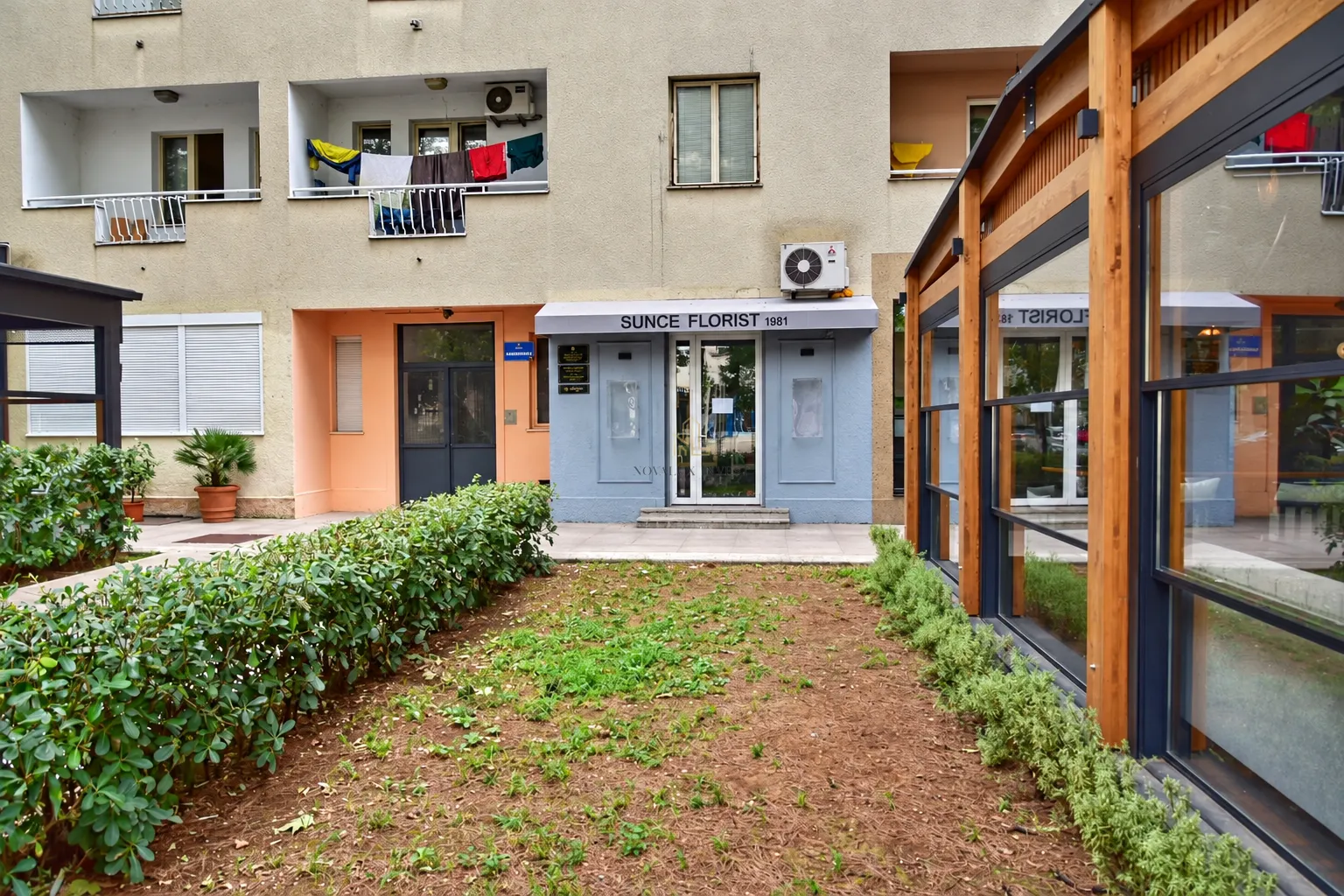 Building exterior with a business space entrance and a landscaped courtyard.