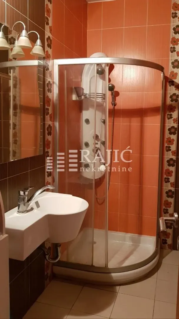 Small bathroom with a shower cabin, washbasin, and mirror.