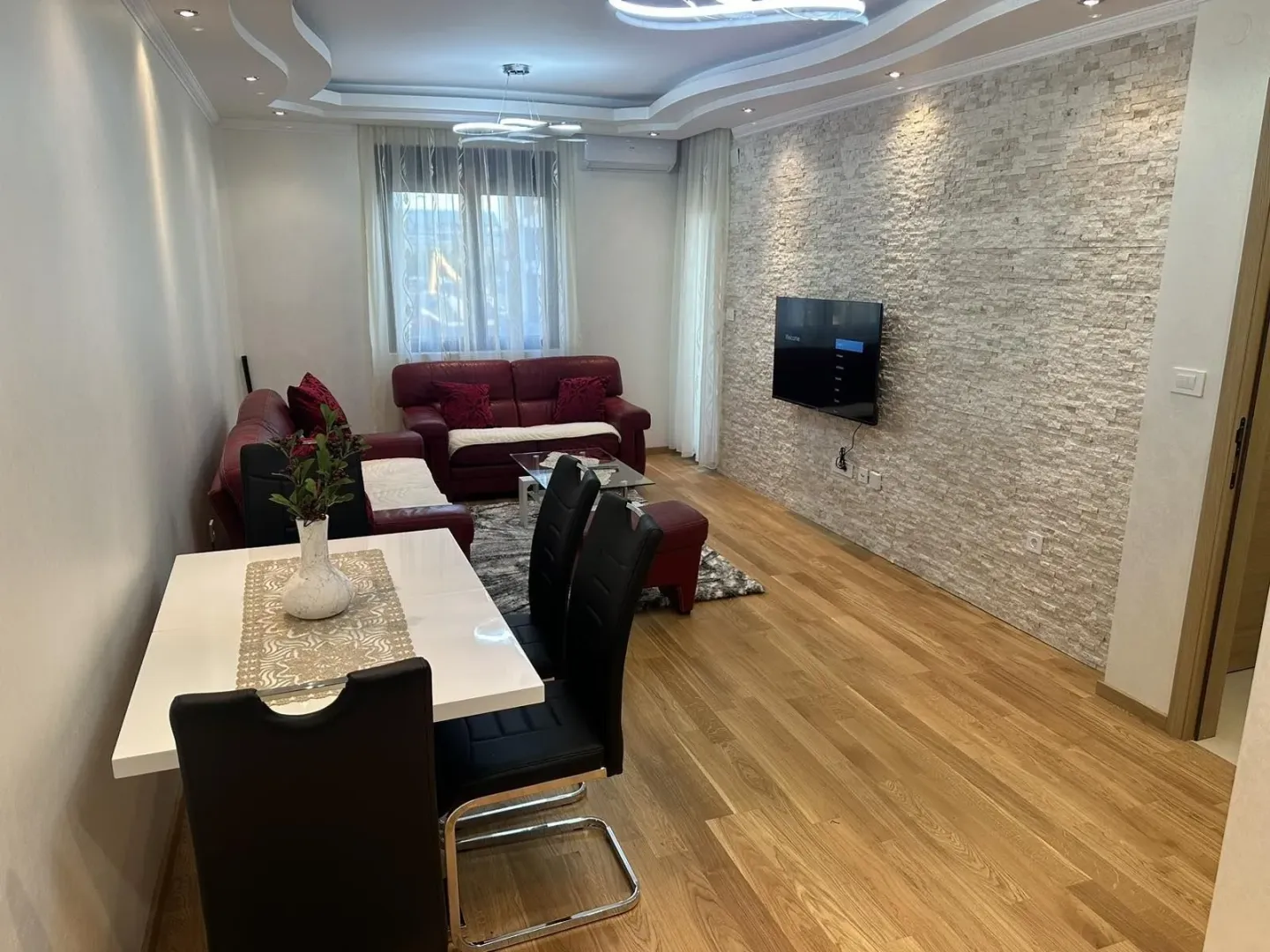 Bright living room with a dining table and a decorative stone wall.