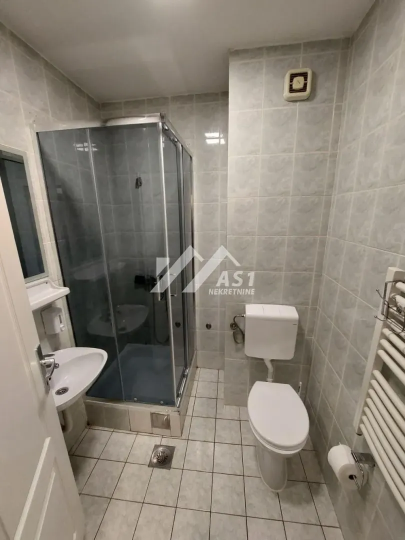 Kupatilo sa tuš kabinom, umivaonikom i toaletom obloženo keramičkim pločicama.