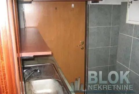 Small kitchen with a sink and wooden cabinets. - image 9