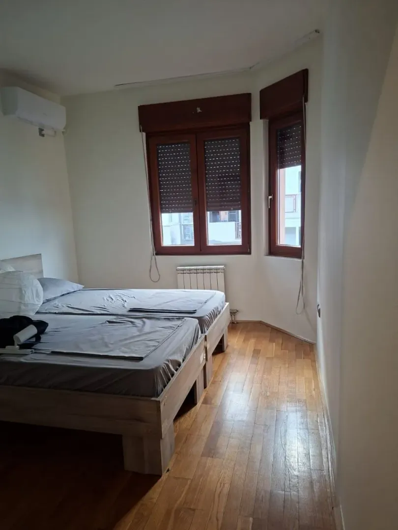 Bedroom with a double bed, wooden flooring, and windows with shutters.