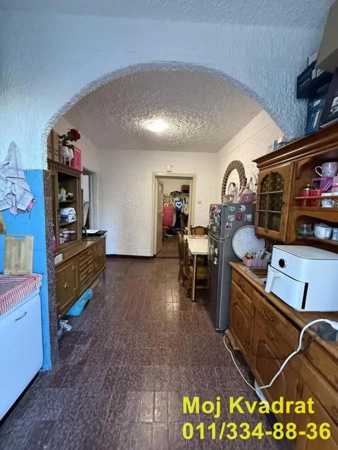 Tradicionalna kuhinja sa drvenim nameštajem i trpezarijskim stolom.