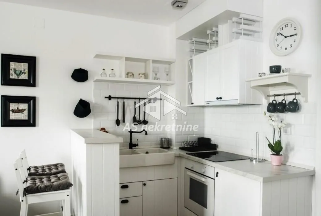 White kitchen with a sink, built-in oven, and a breakfast bar.