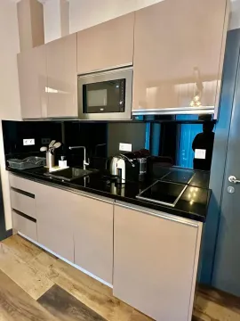 Modern kitchen with beige cabinets and a black countertop. - image 16