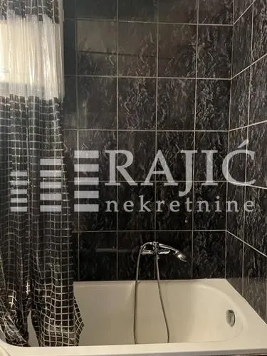 Smaller bathroom with a bathtub and dark tiles.