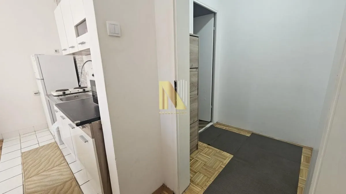 Manja bela kuhinja sa sudoperom i radnom površinom.