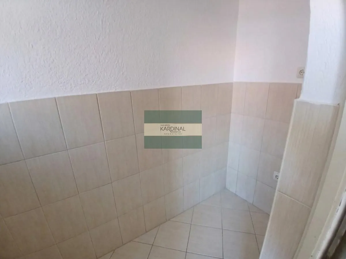 An empty corner of a room tiled with ceramic tiles.