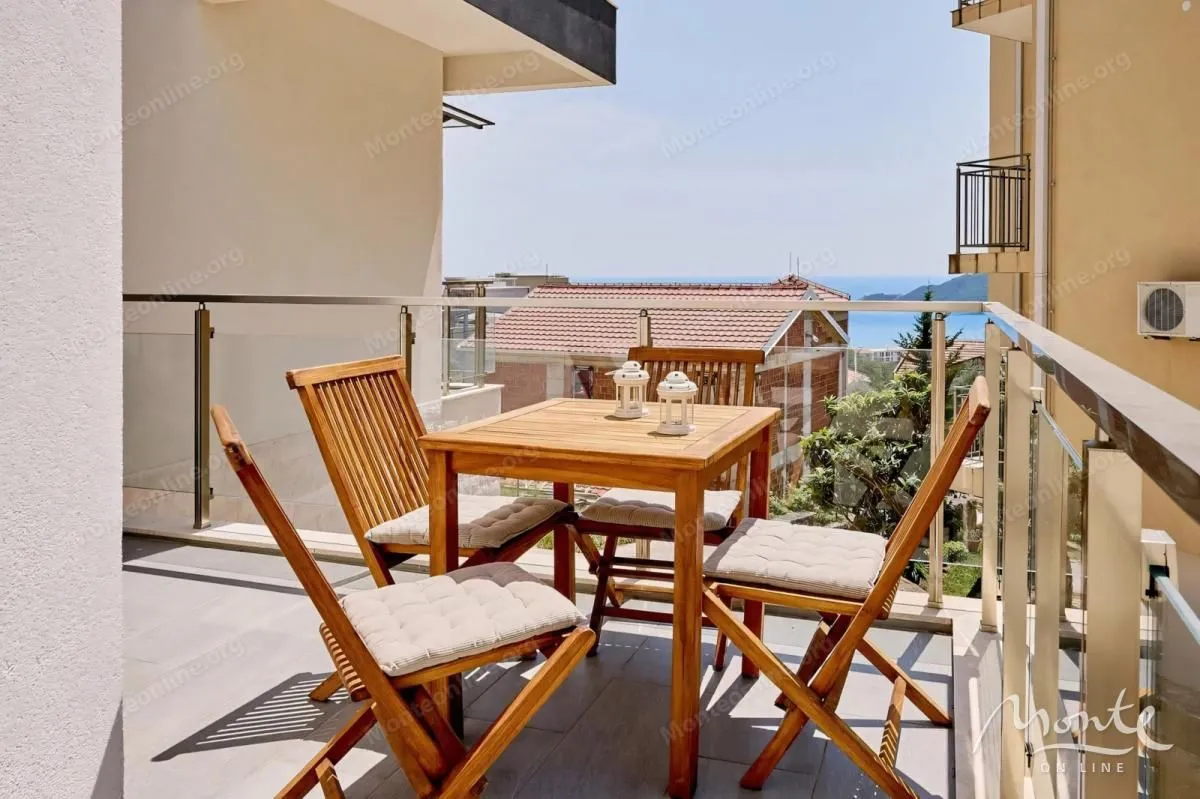 Namješten balkon sa drvenim stolom, stolicama i pogledom na more.