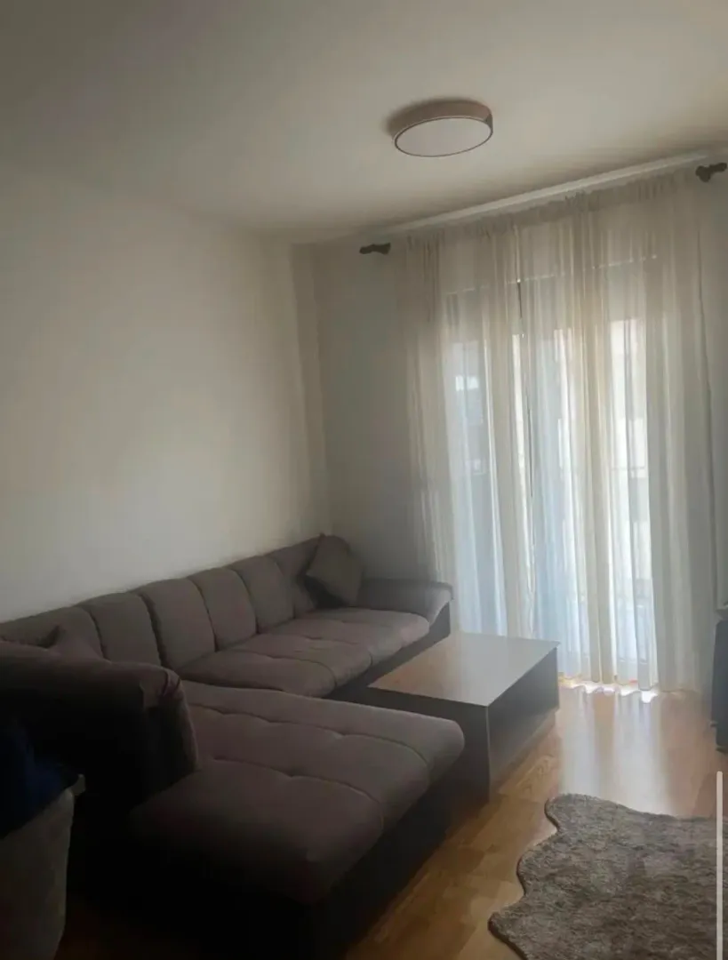 Dnevna soba sa ugaonom garniturom i stočićem pored prozora.