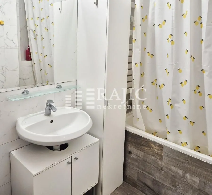 Small bathroom with a sink, mirror, and bathtub with a curtain.