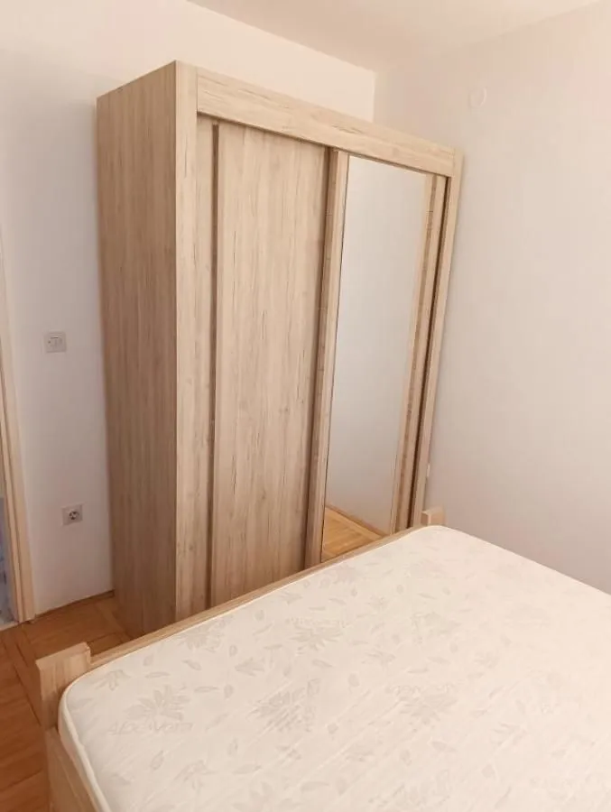 Spavaća soba sa krevetom i drvenim ormarom sa ogledalom.