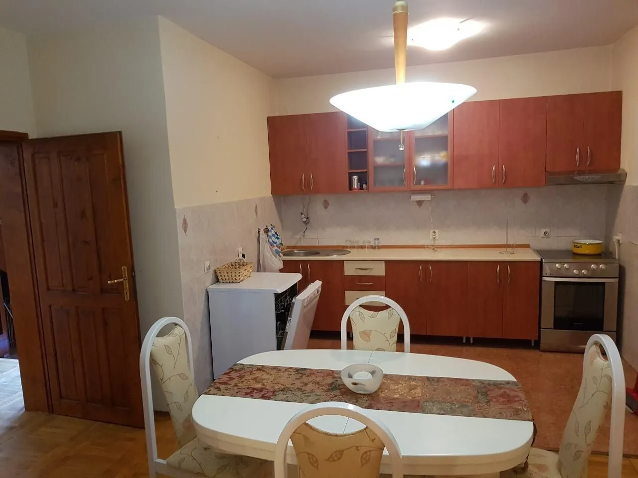 Kitchen with wooden cabinets and a dining table in the foreground.