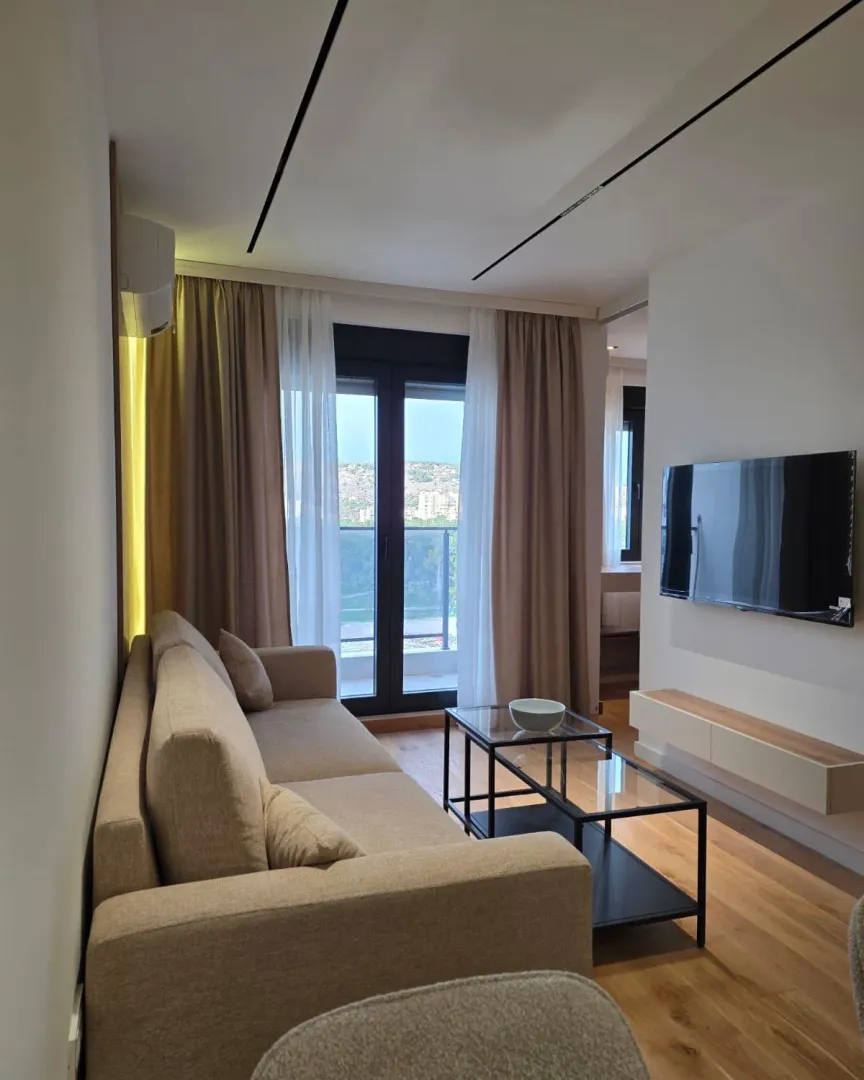 Modern and bright living room with a sofa, TV, and balcony access.