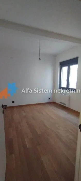 Prazna prostorija sa parketom i prozorom.