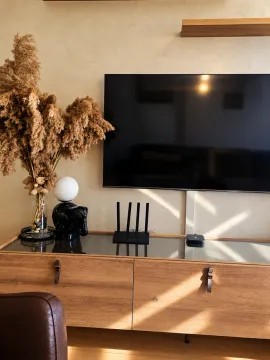 Living room with a wooden chest of drawers, TV, and decorative details. - image 3