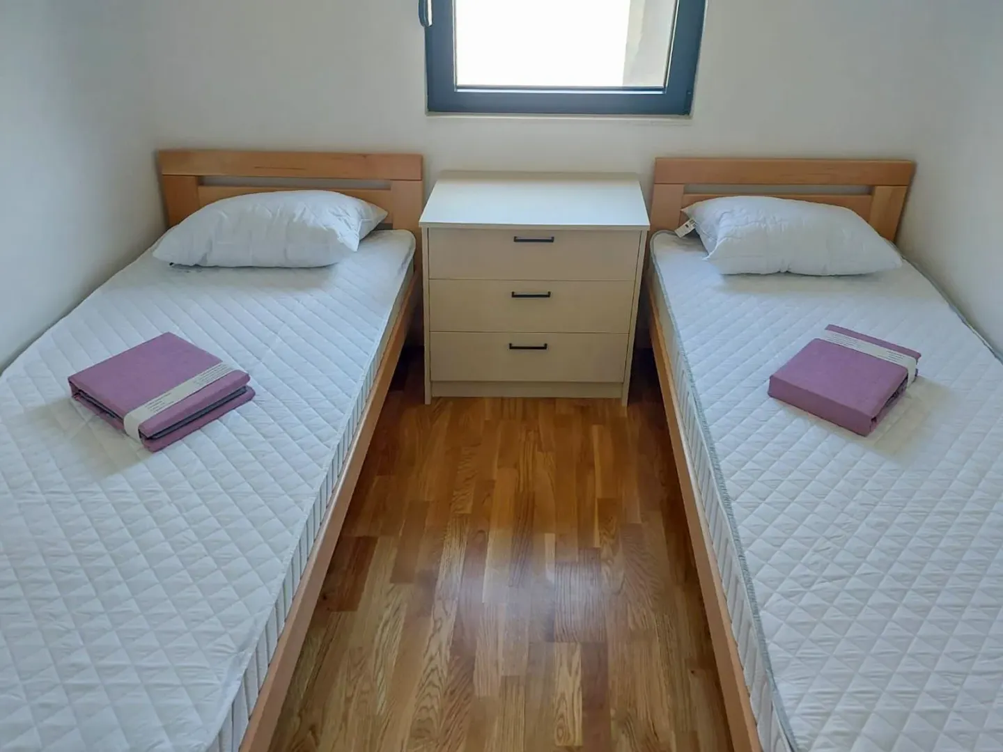Spavaća soba sa dva odvojena kreveta i noćnim stočićem.