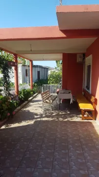 Natkrivena terasa kuće sa stolom, klupama i popločanim podom. - image 3