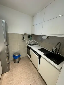 View of a small kitchen with white cabinets and a refrigerator. - image 14