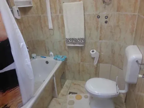 Manje kupatilo sa kadom, toaletom i bež pločicama. - image 14