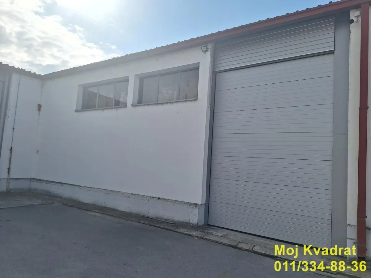 View of the exterior of an industrial building with a roll-up door and windows.