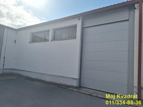 View of the exterior of an industrial building with a roll-up door and windows. - image 10
