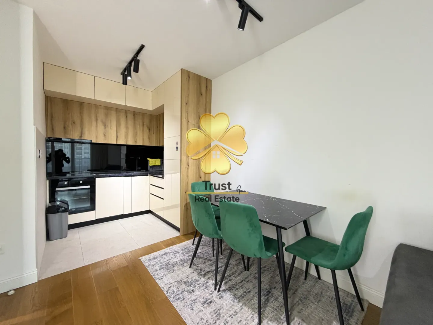 Modern kitchen with a dining table and green chairs.