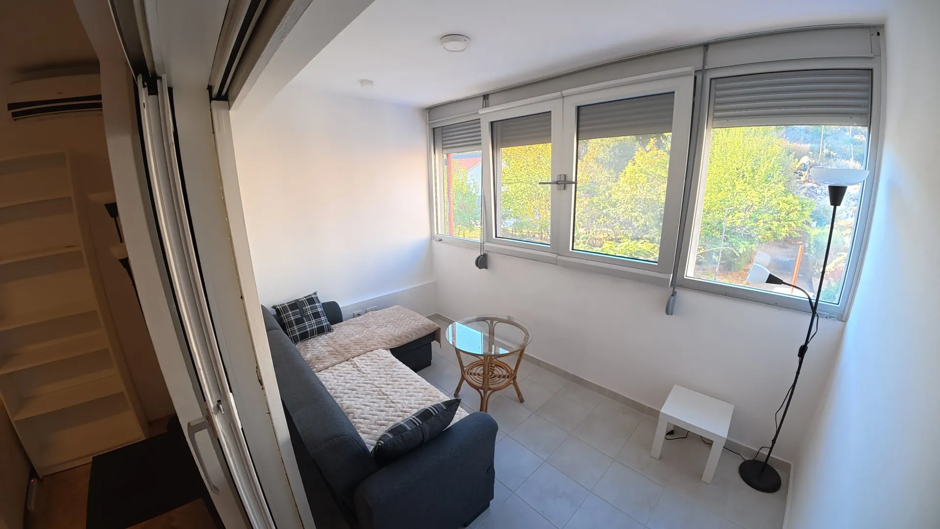 Bright living room with a sofa seating area and a view through a large window.