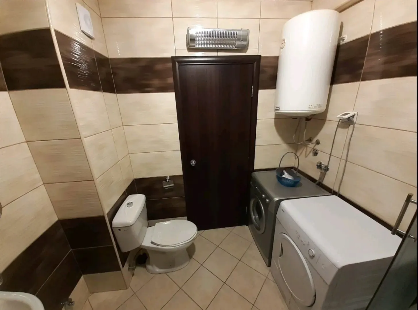 Kupatilo sa toaletom, bojlerom, veš mašinom i mašinom za sušenje veša.
