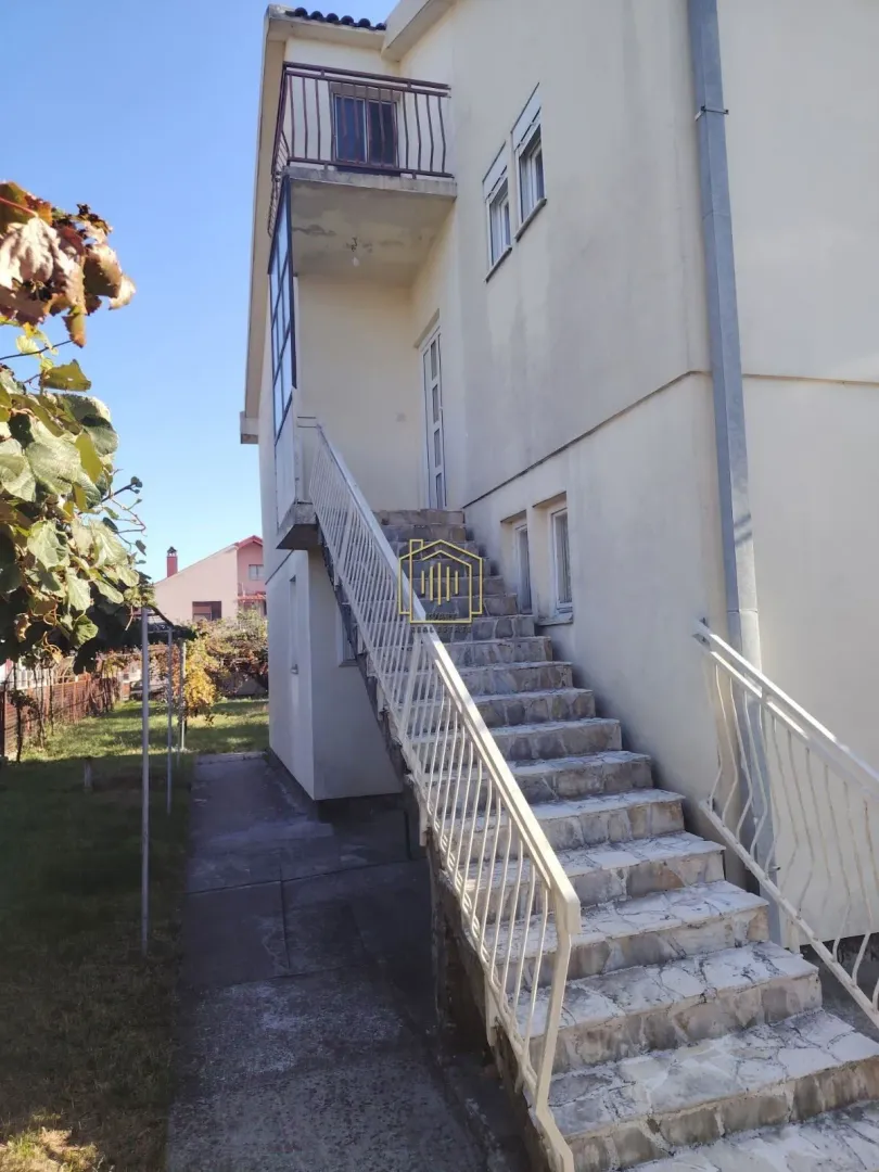 Spoljne stepenice koje vode na sprat kuće sa balkonom i dvorištem.