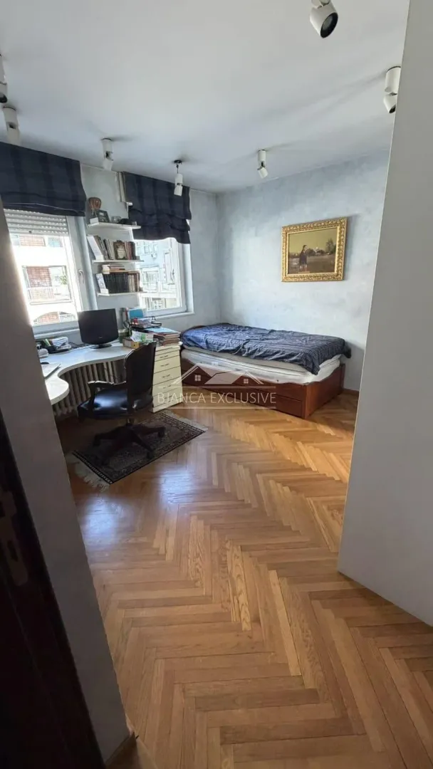 Manja spavaća soba sa krevetom i radnim stolom ispod prozora.