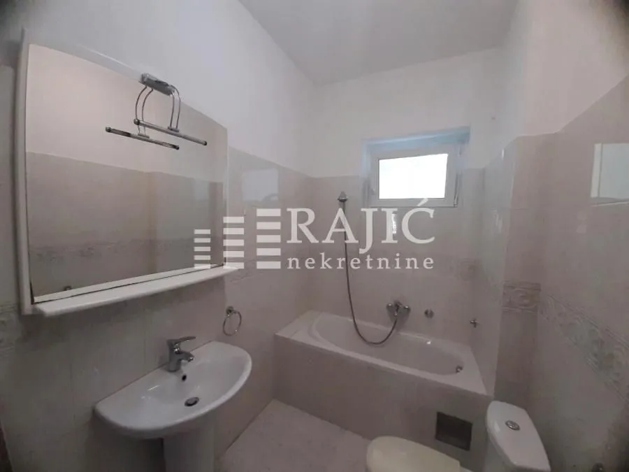 Smaller bathroom with a bathtub, washbasin, and toilet.